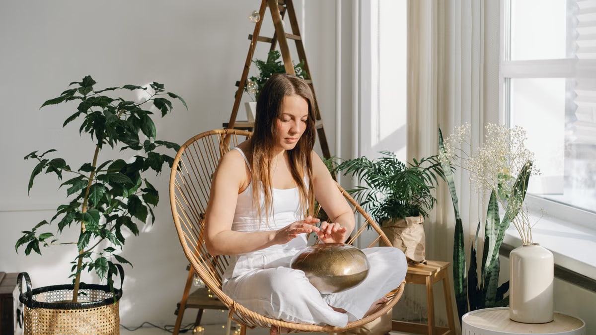 A woman meditates indoors surrounded by houseplants, creating a calming atmosphere.