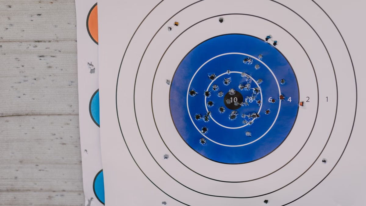 A blue and white archery target with numerous hit marks depicting precision practice.